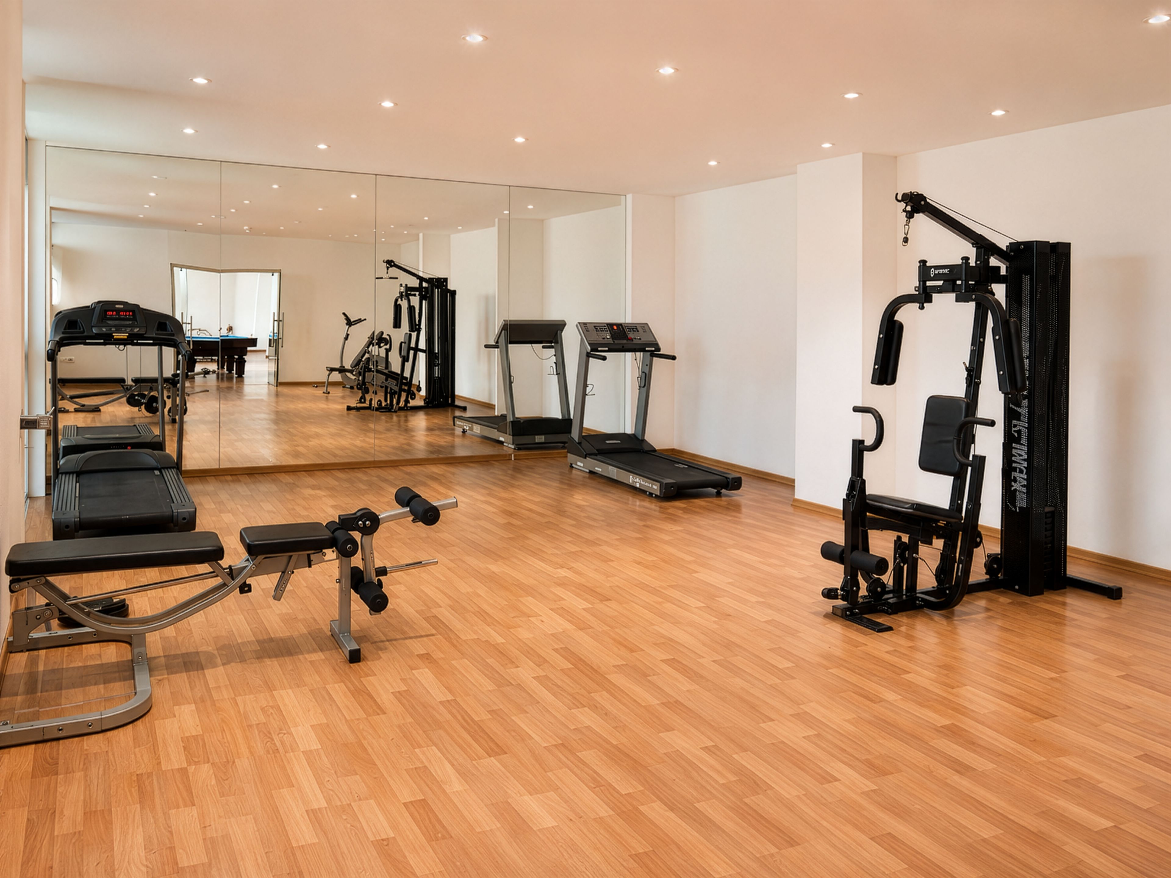 Academia com equipamentos de ginástica, piso de madeira e um espelho grande.