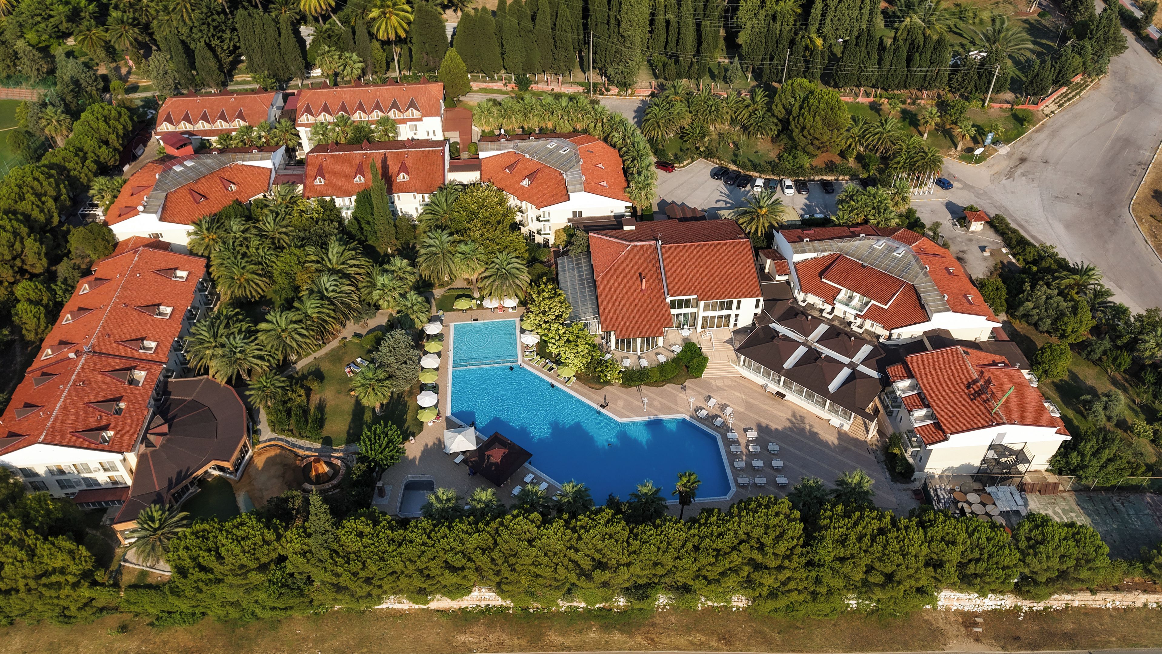 Ein Luftbild eines Wohngebiets mit mehreren Häusern, einem Swimmingpool und umgebender Bepflanzung.