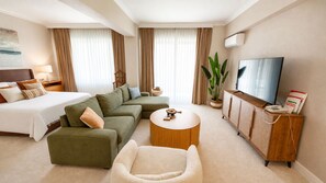 A hotel room with a bed, sofa, armchair, round coffee table, TV, and a cabinet with a telephone. - Lycus River Thermal Hotel (Denizli)