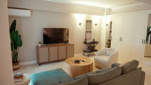 A living room with a flat-screen TV, a sofa, a coffee table, a cabinet, and a plant. - Lycus River Thermal Hotel (Denizli)