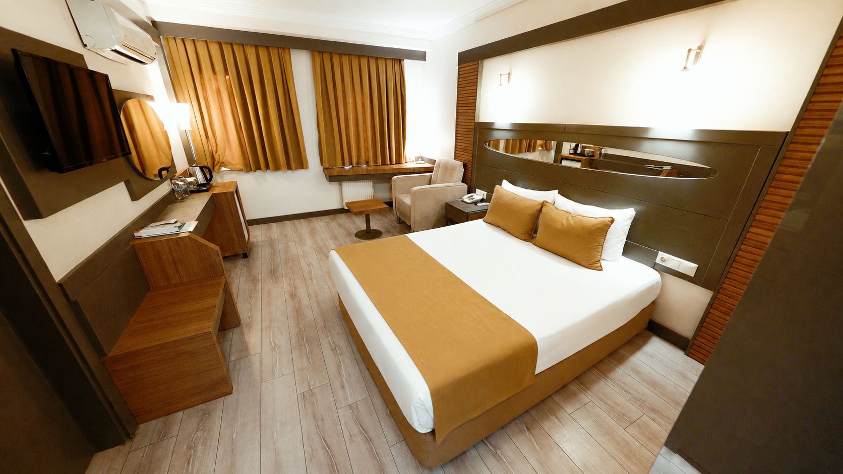 Una habitación de hotel con una cama grande, un escritorio, una silla y un televisor.