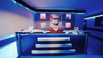 Un mostrador de recepción con una disposición de toallas con forma de corazón, una obra de arte enmarcada encima y una escalera que conduce a un nivel superior.