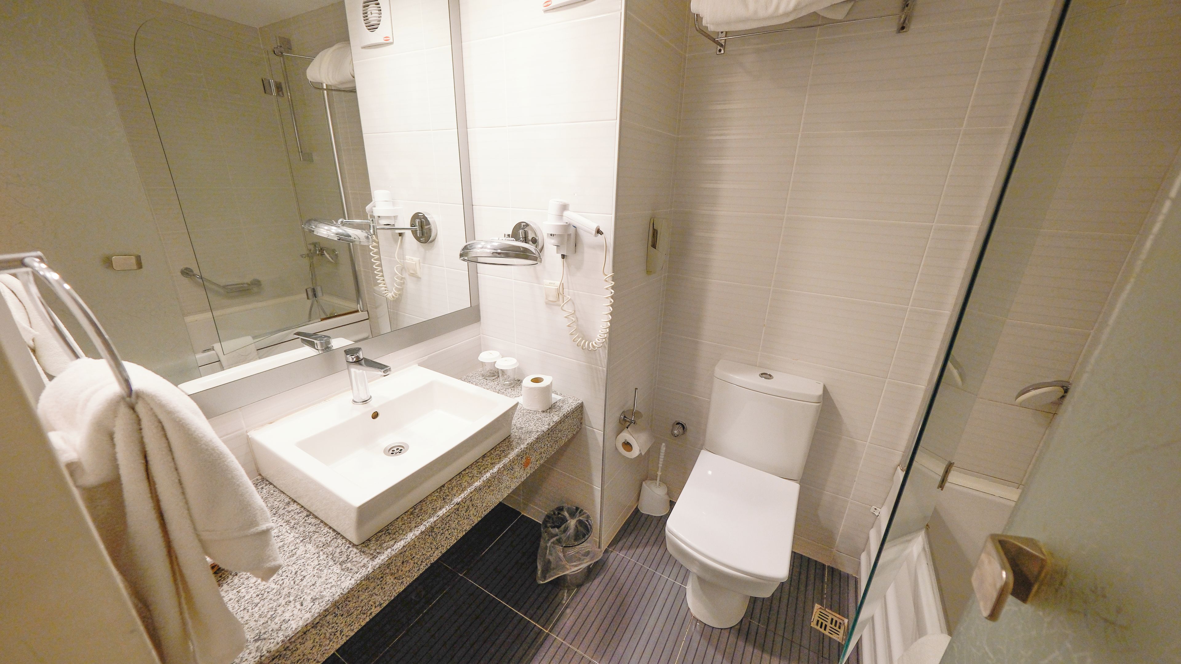 Un baño con lavamanos, inodoro y zona de ducha.