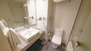 Un baño con lavamanos, inodoro y zona de ducha.
