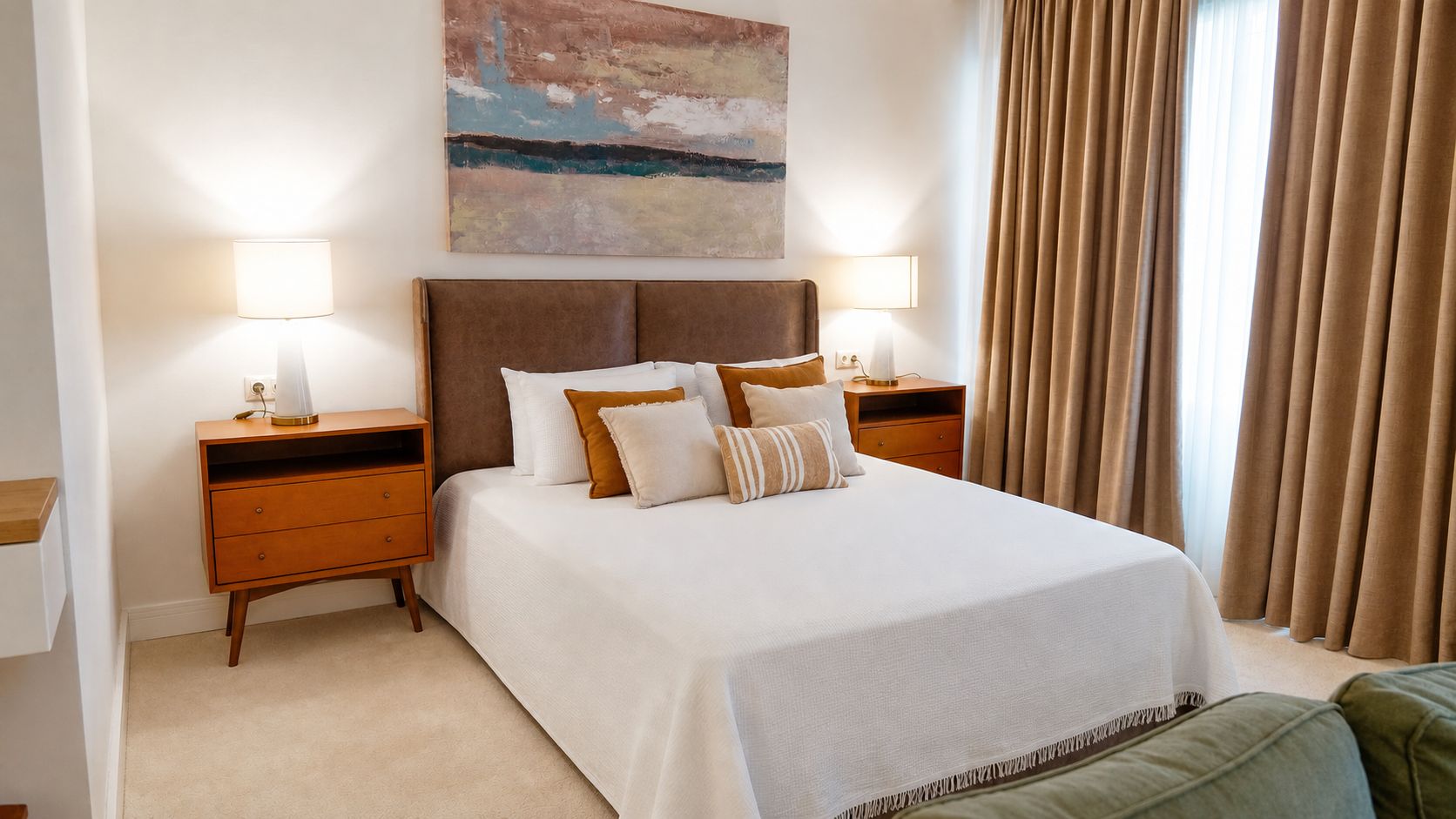 A hotel room with a large bed, two bedside tables, a nightstand, a painting on the wall, and a window with curtains.