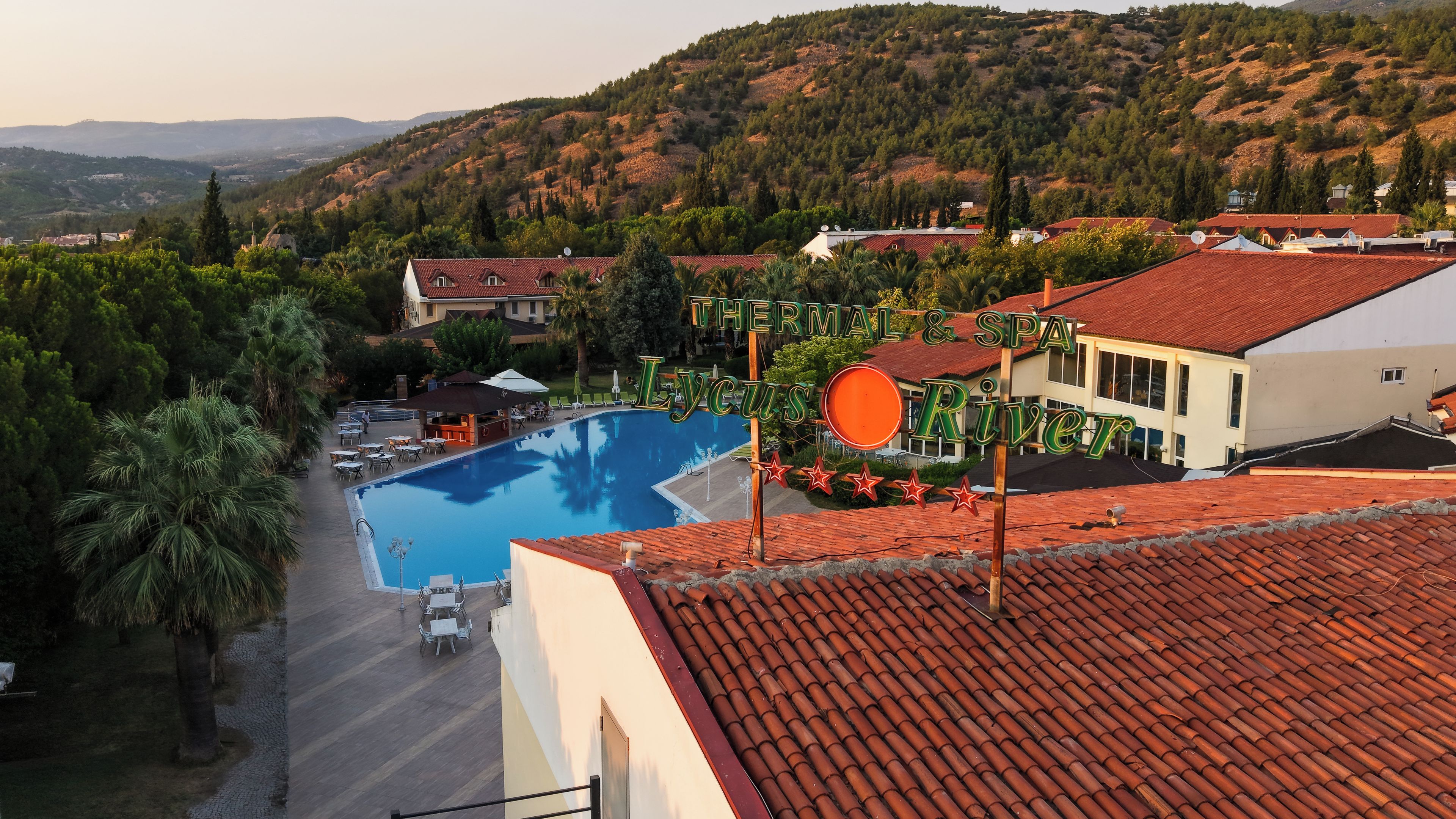 Un hotel con piscina, rodeado de exuberante vegetación y colinas.