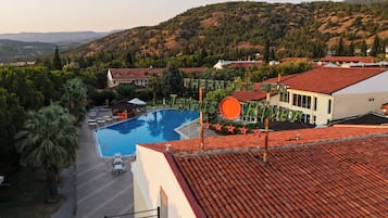 Un hotel con piscina, rodeado de exuberante vegetación y colinas.