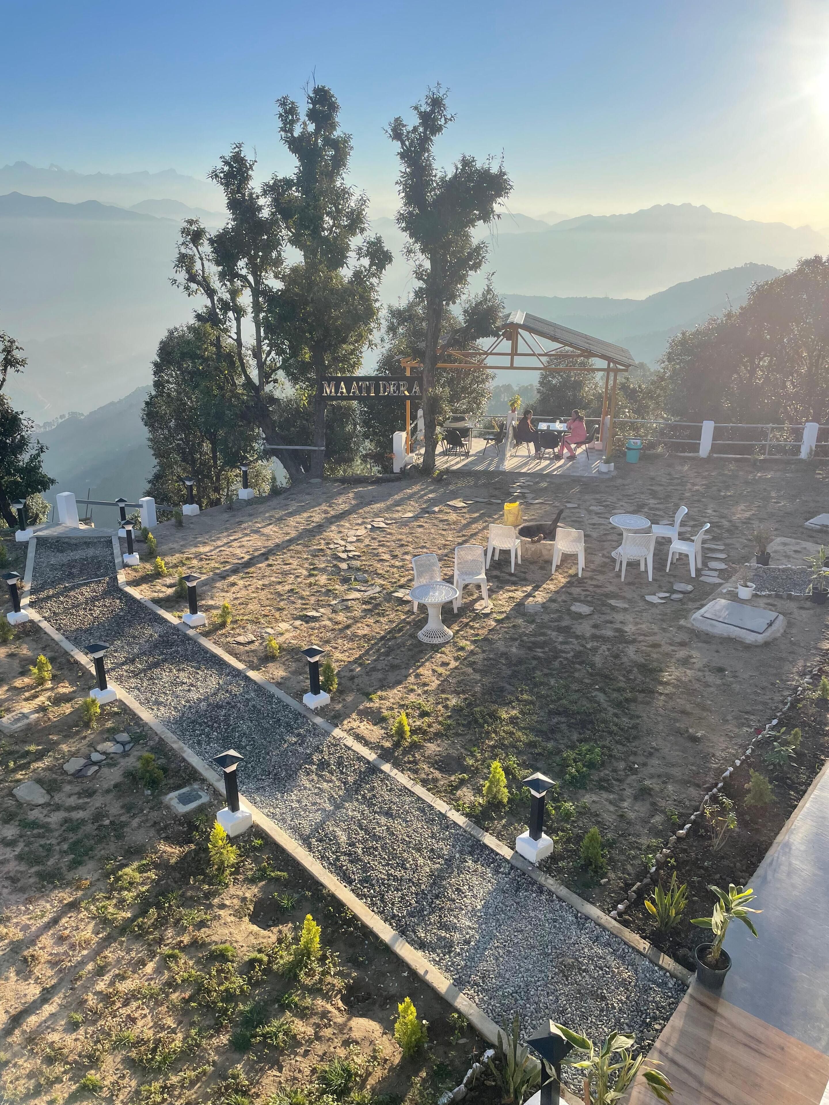 A terrace with outdoor seating, a pergola, and a sign reading "MAATI DERA".