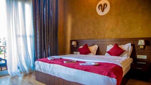Un lit bien fait, avec une literie rouge et blanche, une tête de lit en bois et une décoration en forme de cœur fixée au mur.