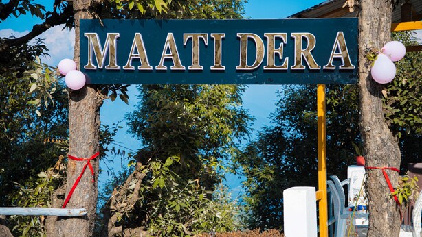 A sign with the name "MAATI DERA" attached to a tree, surrounded by greenery and balloons. - Maatidera Resort-Boutique himalaya stay (Tehri)