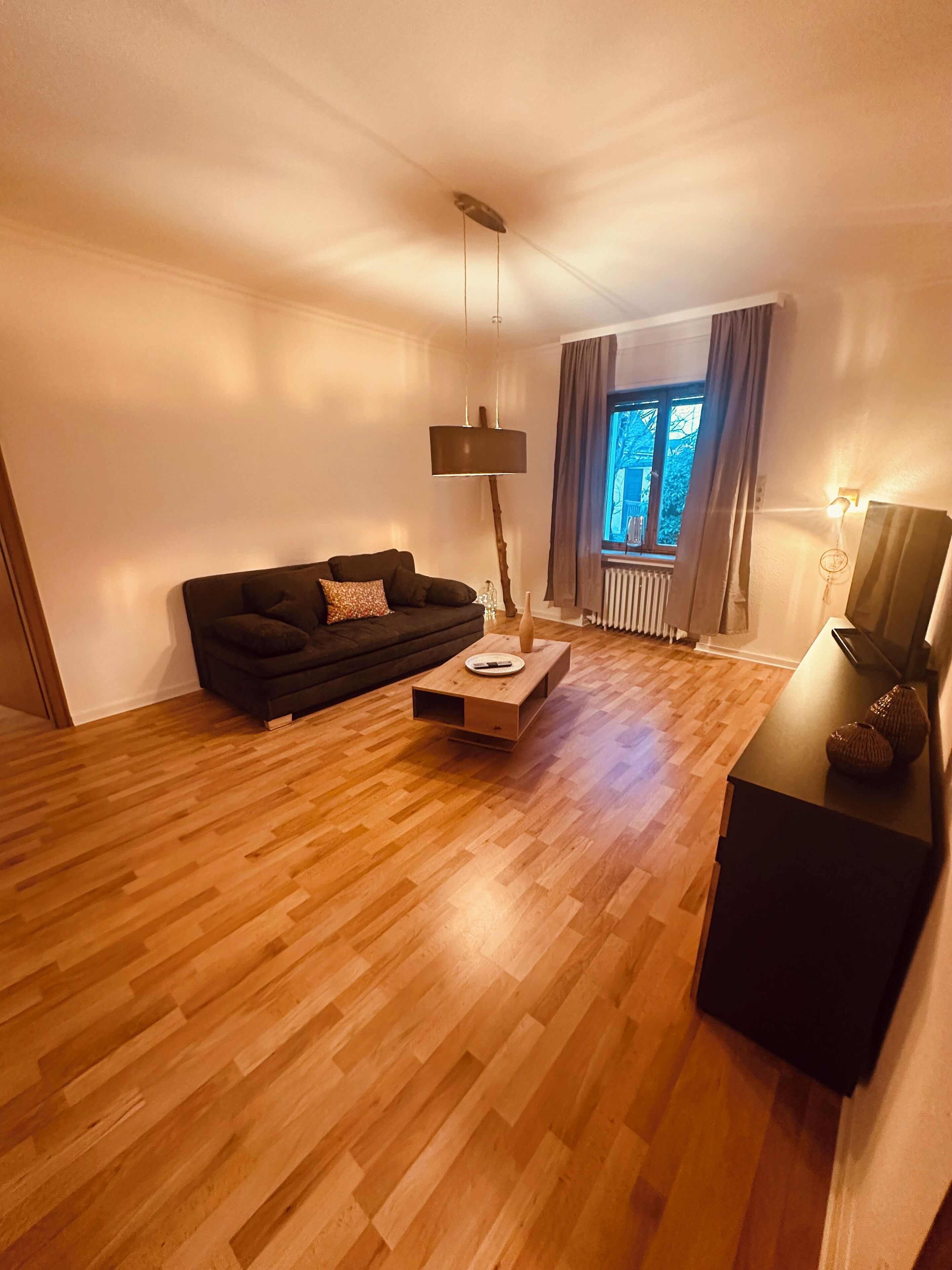 Un saló modern amb un sofà fosc, una taula baixa de fusta i una làmpada de peu.