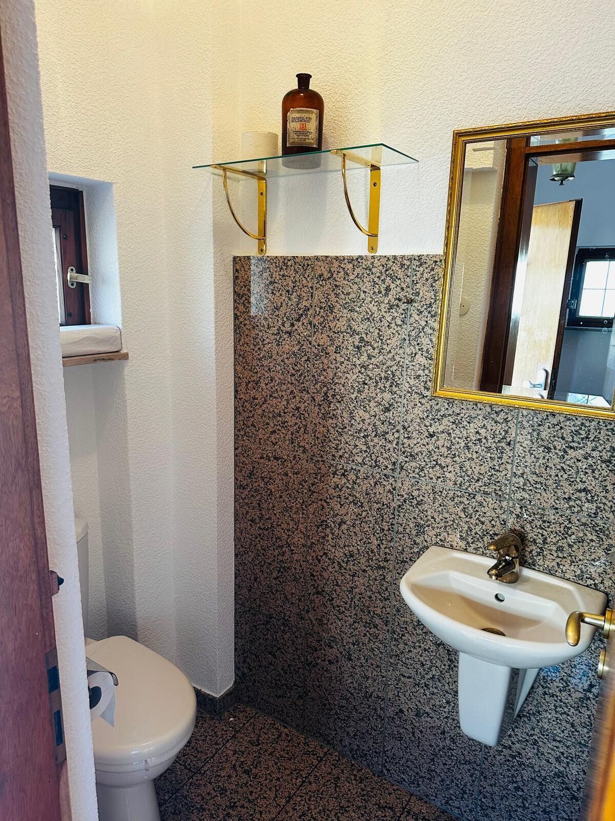 Ein kleines Badezimmer mit Toilette, Waschbecken und Spiegel.