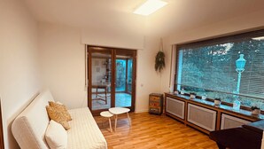 Una sala de estar con un sofá blanco, una mesita y una ventana con persianas.