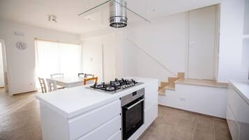A modern kitchen with a central island, built-in oven, and a glass pendant light.