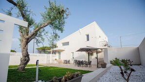 A modern house with a patio, outdoor furniture, and a tree. - Homidoo BellaVita Apartment (Pachino)