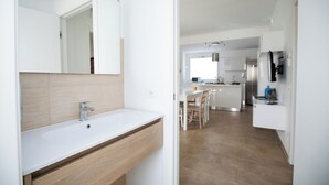 A modern kitchen with white cabinetry, a stainless steel refrigerator, and a dining area with a table and chairs. - Homidoo BellaVita Apartment (Pachino)