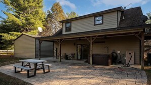A two-story house with a covered patio, a hot tub, and a garage.