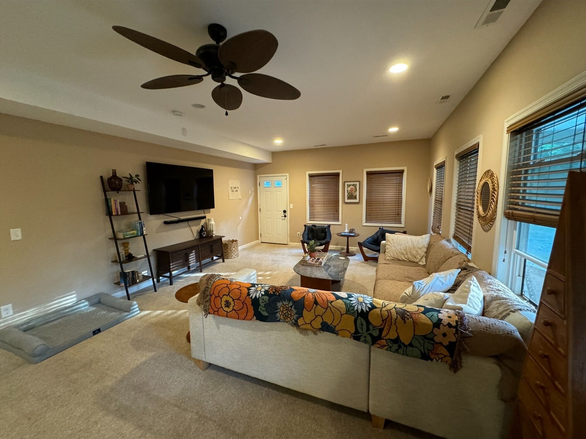 Un salon avec un canapé, une table basse, un téléviseur et un ventilateur de plafond.