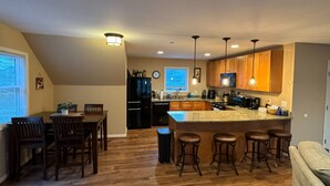 A modern kitchen with wooden cabinets, a granite countertop, and bar stools.