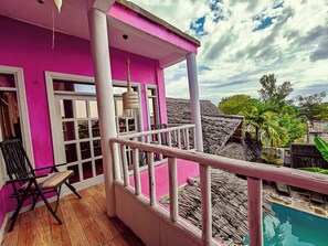 A pink building with a balcony overlooking a pool. - Nungwi Roses Lodge (Nungwi)