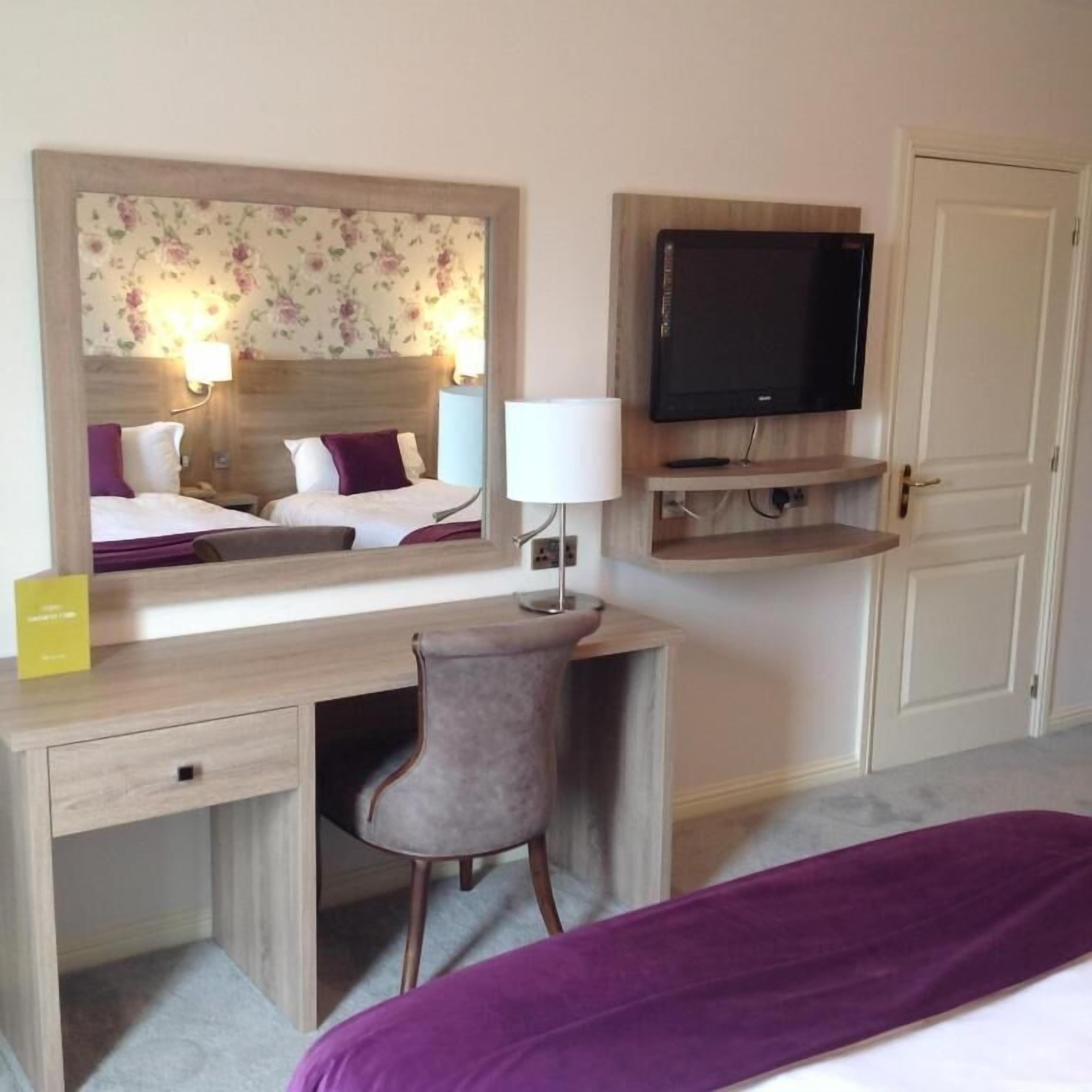 Une chambre d’hôtel comprenant un lit, un bureau avec une chaise, une télévision et un miroir.
