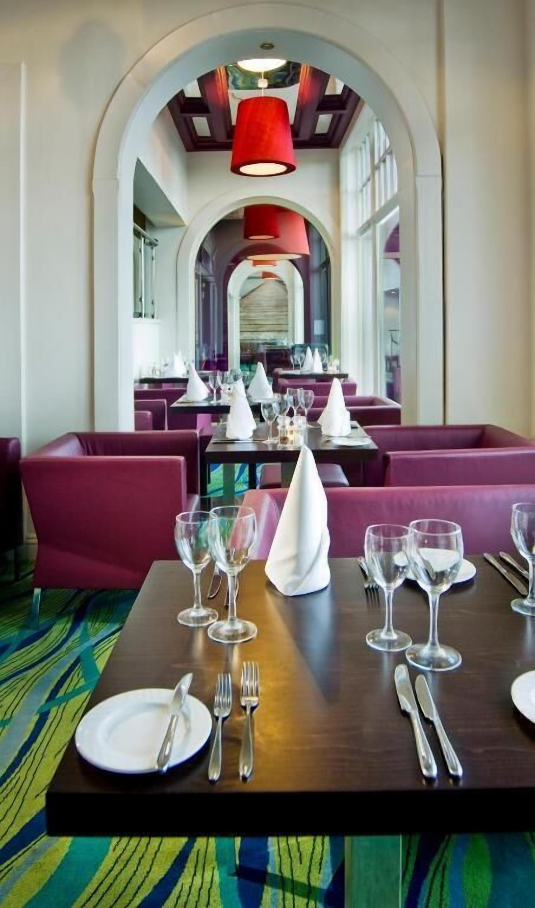 A restaurant with a central dining table set for four, surrounded by red upholstered booths.