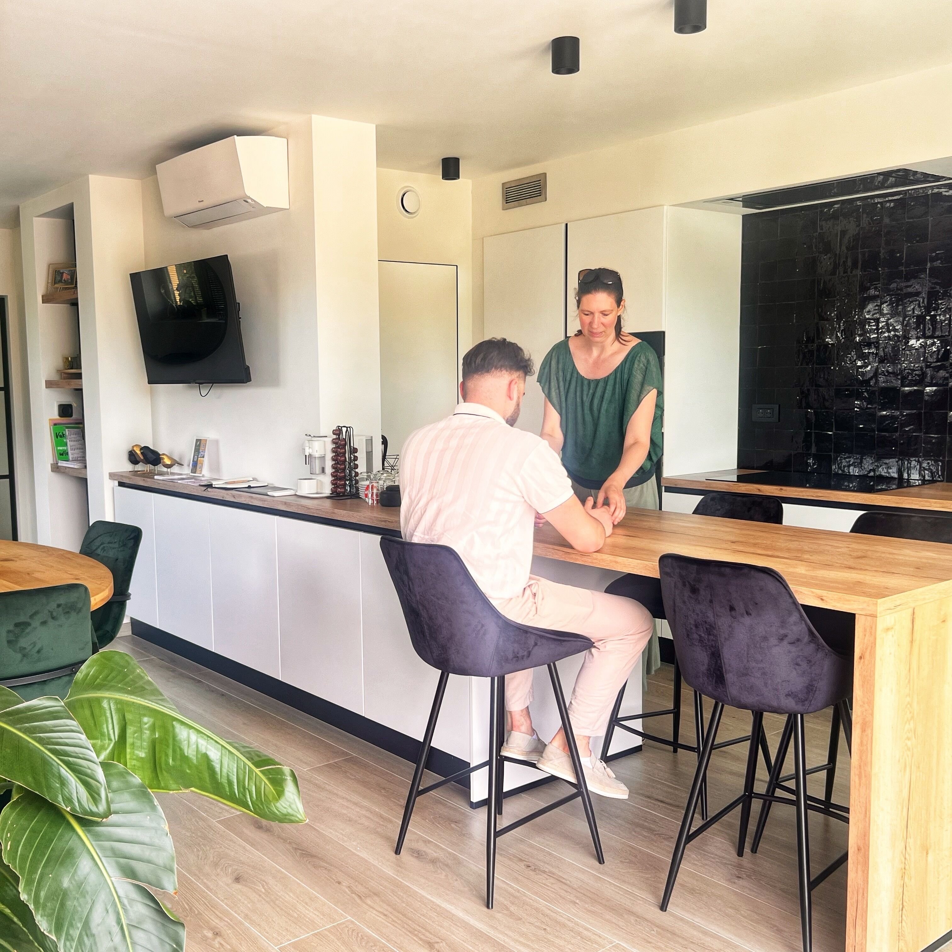 A modern kitchen with a central island, bar stools, and a large mirror.
