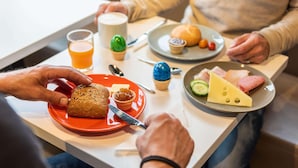 Una colazione con diversi cibi, tra cui pane, formaggio e un muffin, su un tavolo.