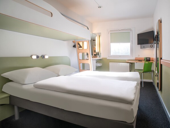 Ein Hotelzimmer mit einem Bett, einem Schreibtisch, einem Sessel, einem Spiegel und einem Fernseher.