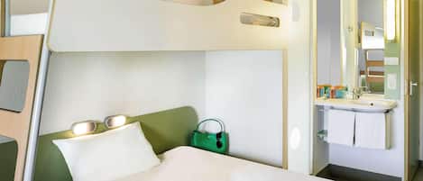 Una cama litera con una mesita de noche, una bolsa verde y una tableta sobre la cama.