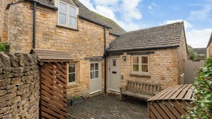 A stone building with a wooden bench and a door. - Newly Refurbished Cosy Cottage in the Heart of Chipping Campden (Chipping Campden)