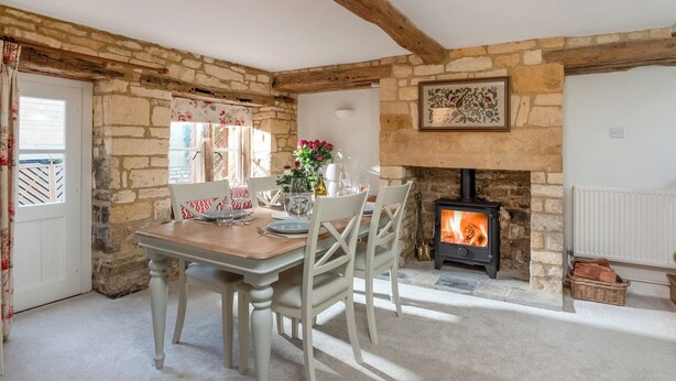 A cozy dining area with a stone fireplace, wooden beams, and a table set for four. - Newly Refurbished Cosy Cottage in the Heart of Chipping Campden (Chipping Campden)