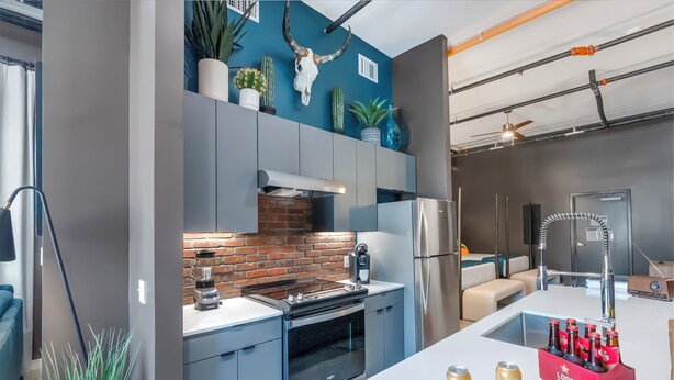 Een moderne keuken met een tegelwand, roestvrijstalen apparatuur en een aanrecht met een drankkoeler en snacks.