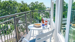 Een balkon met een tafel, twee stoelen en een schaal lekkernijen.