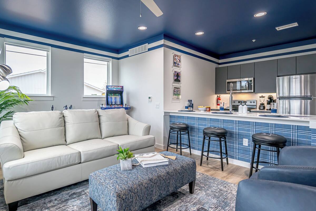 Uma sala de estar moderna com sofá, banqueta e banquetas de bar.