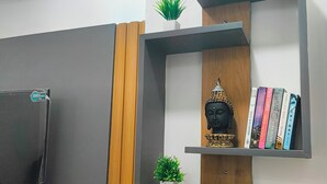 A modern living room with a flat-screen TV mounted on the wall, wooden paneling, and built-in shelves holding decorative items and books.