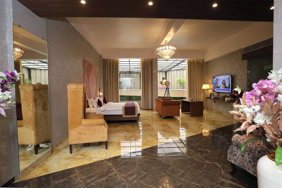 Un amplio vestíbulo de hotel con una cama grande, zona de estar y televisión.