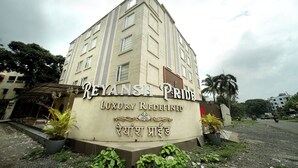 A building with a sign that reads "REYANSH Pride Luxury Redefined" and includes a logo and text in another language. - Hotel Reyansh Pride (Palghar)