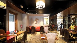 A restaurant interior with wooden flooring, red and brown seating, and a central dining table.
