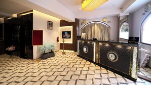 A reception area with a patterned floor, a reception desk, a chandelier, and a clock on the wall. - Hotel Reyansh Pride (Palghar)