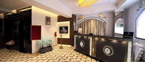 A reception area with a patterned floor, a reception desk, a chandelier, and a clock on the wall.