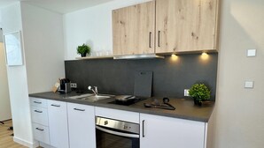 Eine moderne Küche mit weißen Schränken, einer Edelstahl-Spüle und einem Einbauofen.
