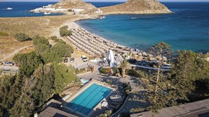 Ein Luftbild eines Küstenresorts mit Schwimmbad, Strandsonnenschirmen und Blick aufs Meer.