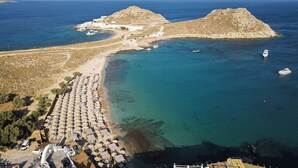 Luftaufnahme einer Küstenregion mit Strand, Booten und einer felsigen Insel.
