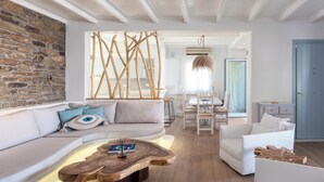 Ein modernes Wohnzimmer mit einer Steinwand, einem Holztisch, einer Couch und einem weißen Sessel.
