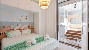 Ein Schlafzimmer mit einem Bett, einer Wandmalerei von Surfern und einer Treppe, die zu einem Außenbereich führt.