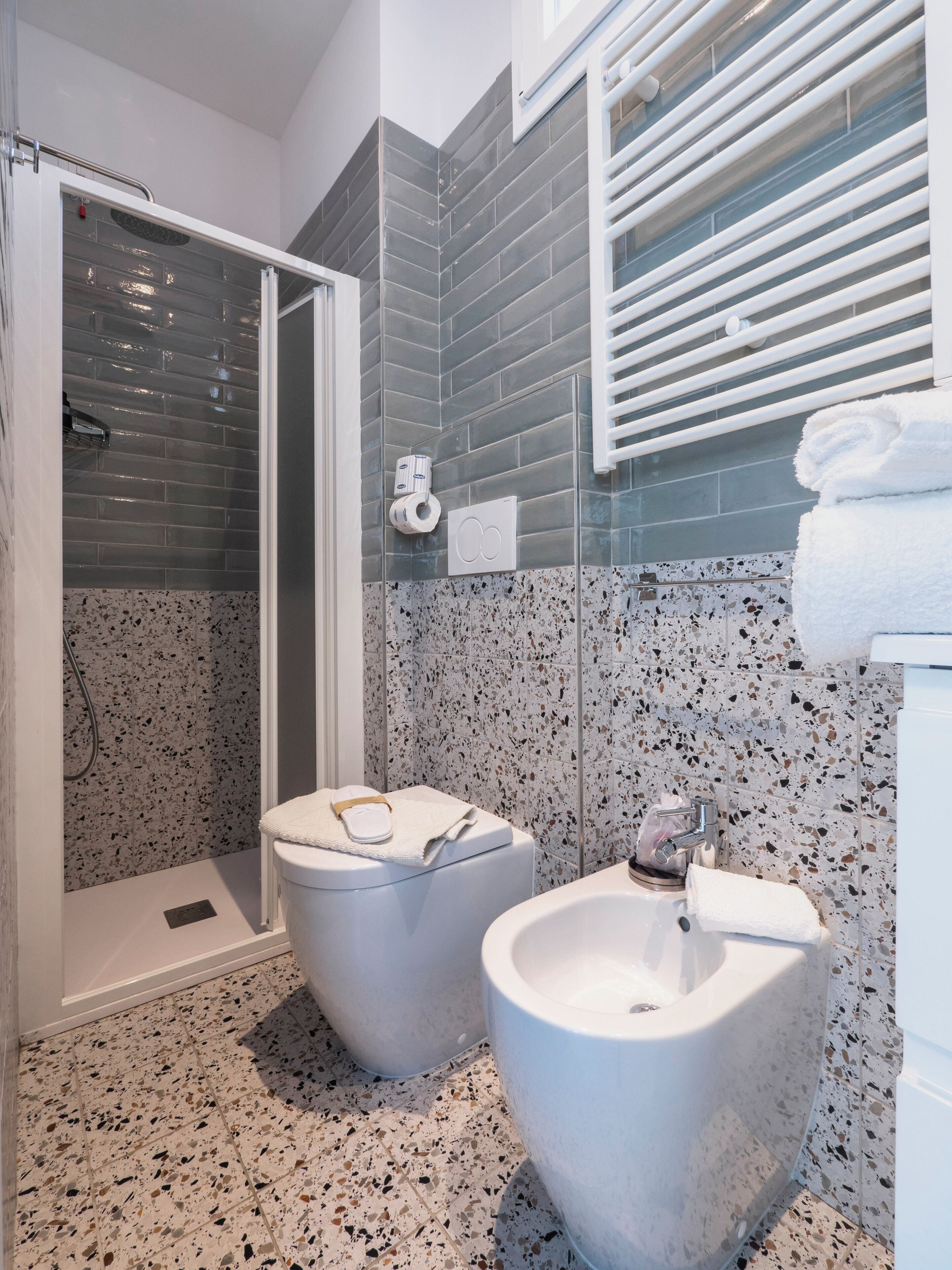 Ein modernes Badezimmer mit Dusche, zwei Bidets und einer Toilette.