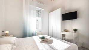 A bedroom with a bed, a desk, a chair, a TV, and a window with curtains. - Zuara9room RIMNI Bed&Breakfast (Rimini)
