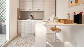 A modern kitchen with light wood cabinets, a white countertop, and a small bar stool. - Zuara9room RIMNI Bed&Breakfast (Rimini)