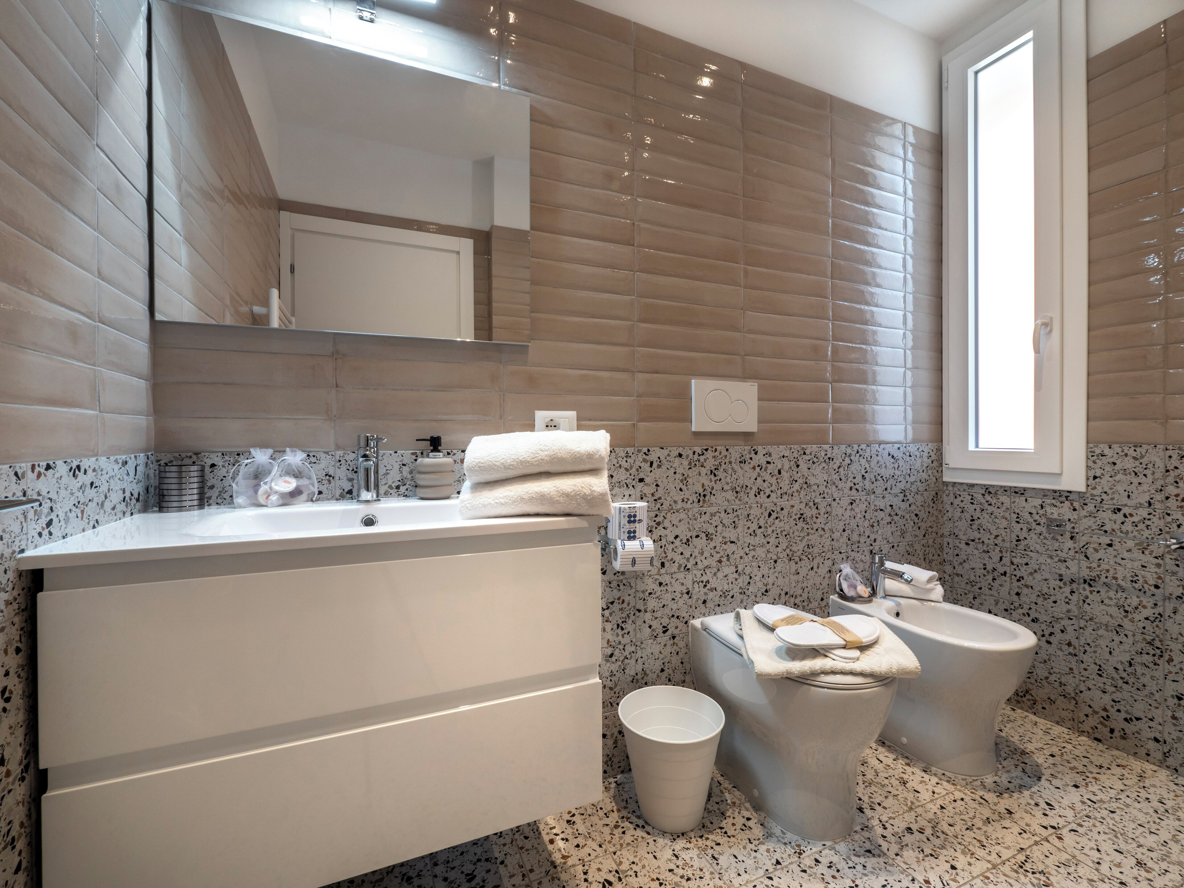 Un baño moderno con un espejo grande, un lavamanos, un inodoro y un bidé.